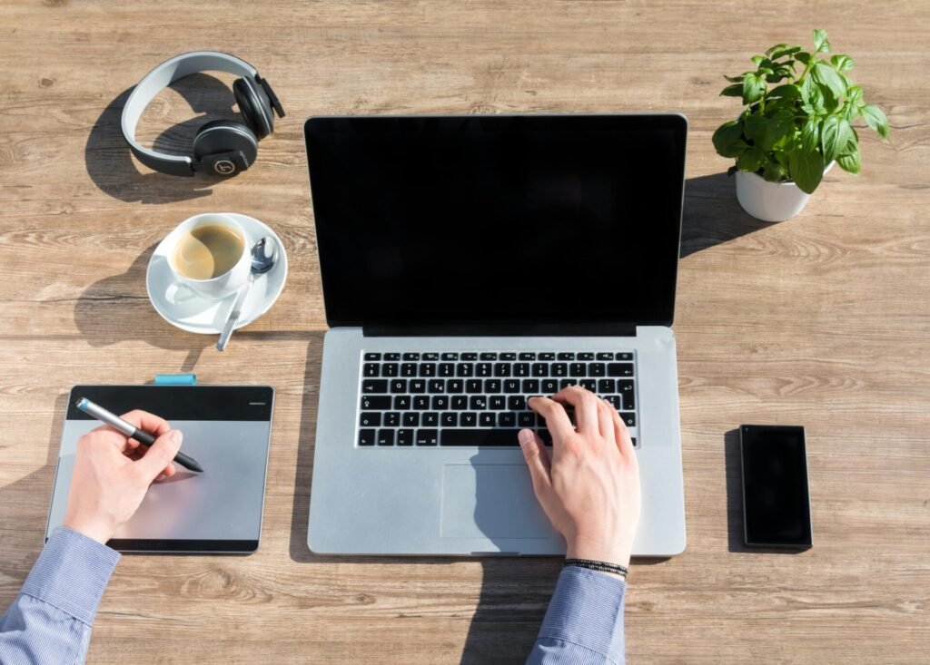 A stylish home office workspace featuring a laptop, drawing tablet, and coffee on a wooden desk.